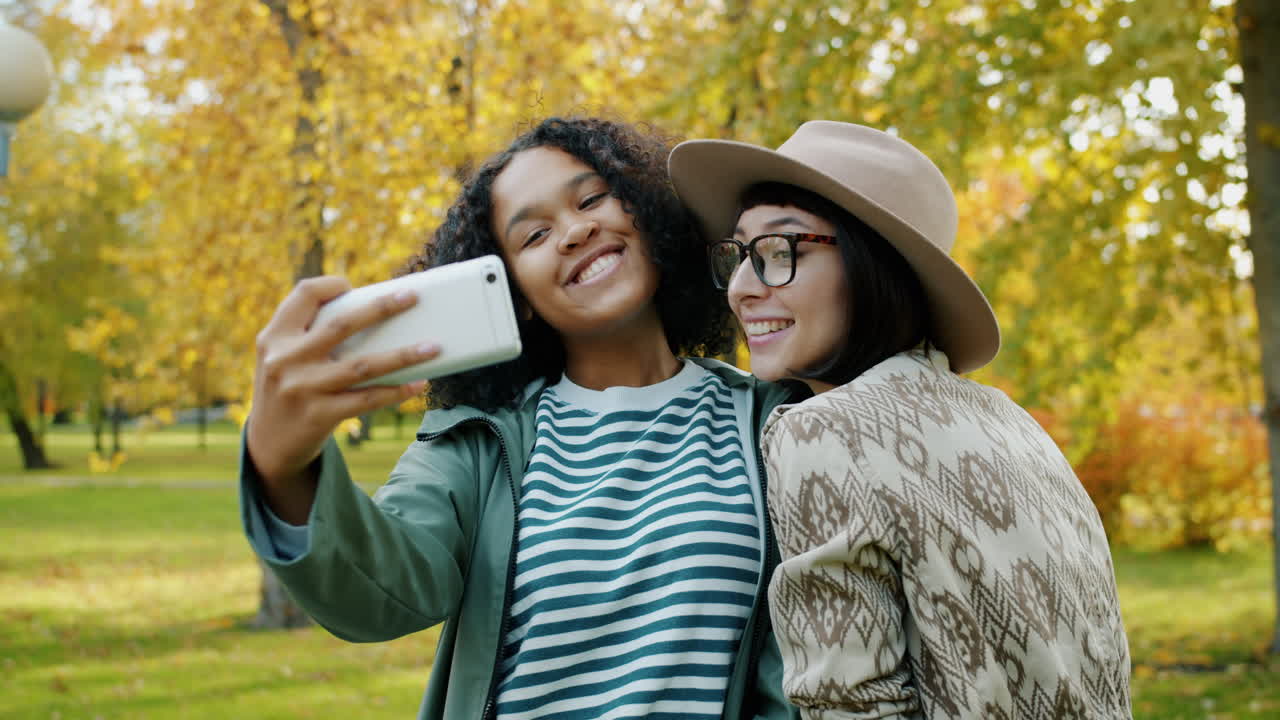 Two friends taking a selfie in an autumn park