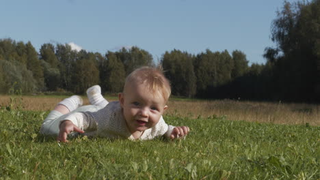 playful smiling baby lying on the grass holding himself up