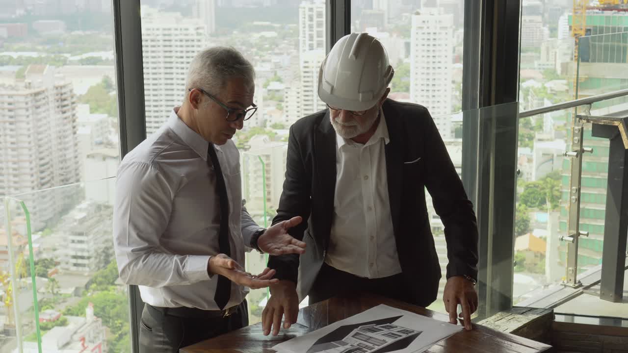 arquitecto maduro hablando con el gerente senior de negocios o el propietario del proyecto con un plan de construcción en un edificio alto