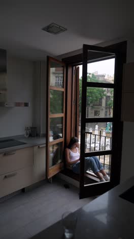 woman reading in kitchen with balcony view