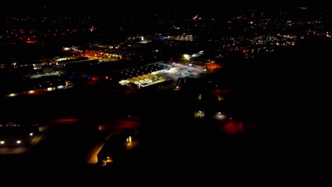 vista aérea nocturna de una vibrante gasolinera en medio de las luces relucientes de la ciudad