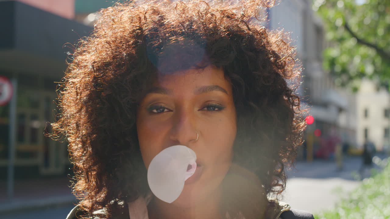 Young trendy girl blowing bubblegum outdoors