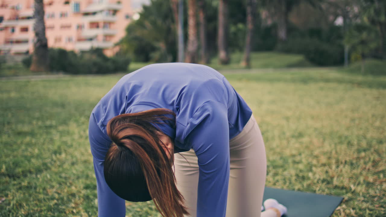 Yoga lady bending back meditating at open air place. Calm woman cat cow pose