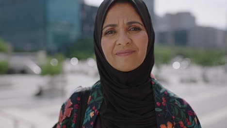 close up portrait of beautiful mature muslim woman smiling friendly at camera in sunny urban city wearing traditional headscarf