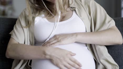 front view of expectant mother resting and listening to music