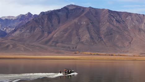 Wake surf surfing water sports MB boat wave Lake Crowley Mammoth Mountain Lakes California aerial drone golden still calm water morning sunny autumn fall family activity follow pan right motion