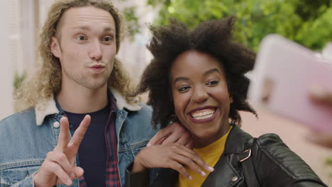 close-up-portrait-of-attractive-young-multi-ethnic-couple-posing-enjoying-taking-selfie-photo-using-smartphone-making-faces-lively-urban-youth