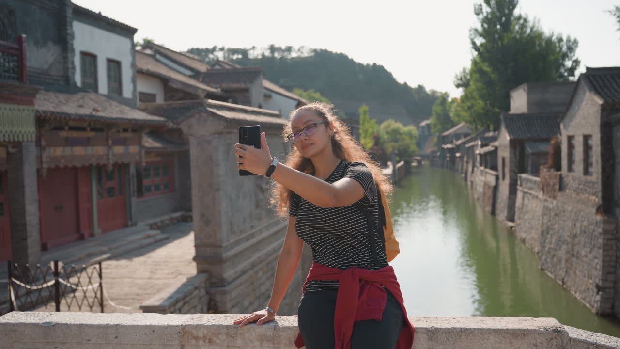 Scena urbana pacifica. Una donna osserva con serenità il suggestivo panorama cittadino. Scena serena di una signora che ammira la vista storica della città. Donna rilassata su un ponte che si gode i tranquilli riflessi dell'acqua e la luce del sole.