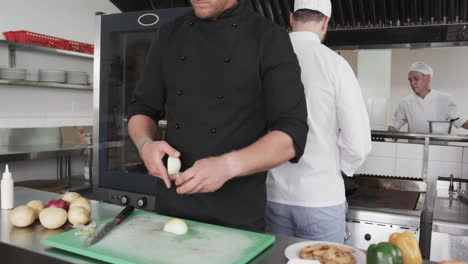 Focused-caucasian-male-chef-cutting-vegetables-in-kitchen,-slow-motion