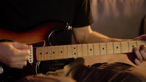 un hombre con pasión toca la guitarra mientras está sentado en el sofá