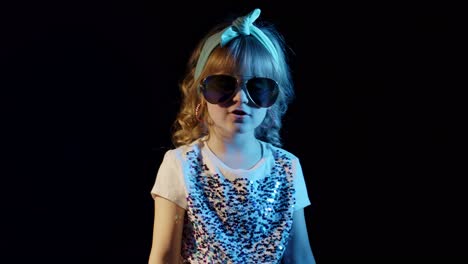 playful blond girl in blue neon lights singing on black background, making faces, fooling around