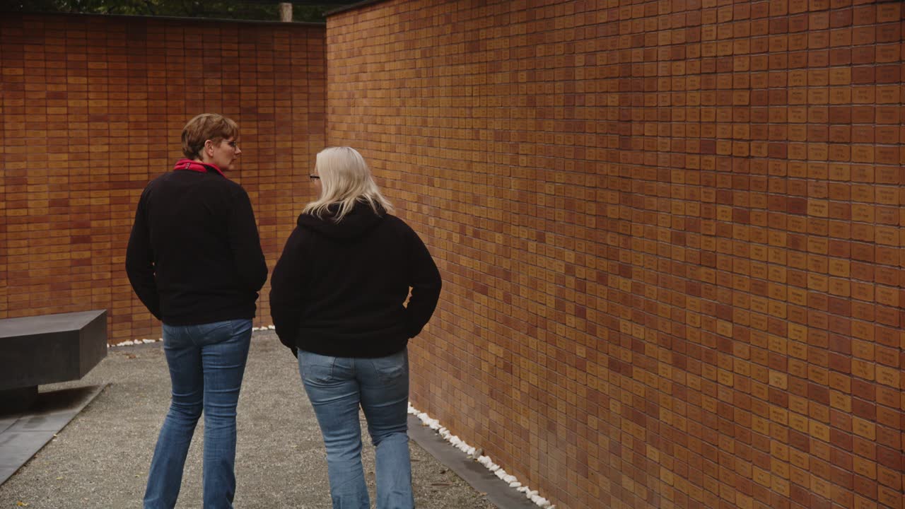 People walking past wall with Holocaust victim names on bricks at the National Holocaust Names Memorial in Amsterdam, the Netherlands
