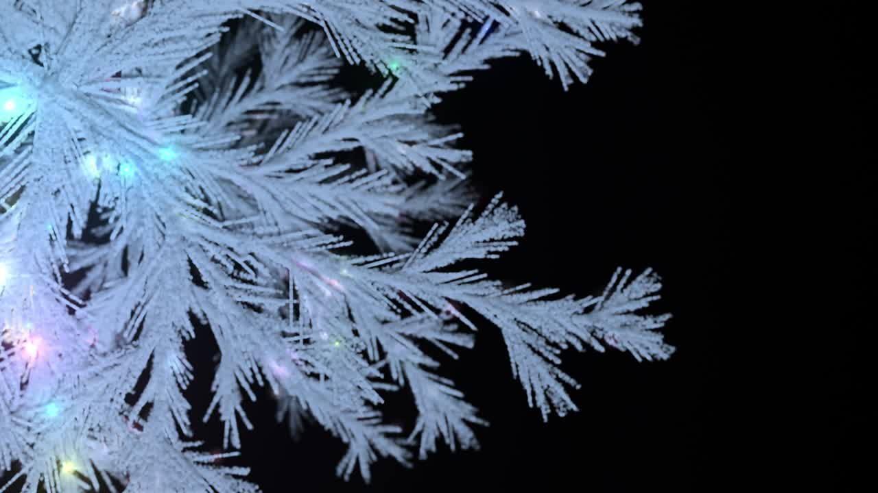 luces intermitentes y árbol de navidad nevado sobre un fondo negro.