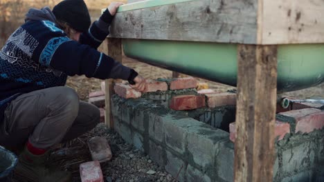 the man is employing cement to anchor the bricks beneath the diy hot tub - timelapse