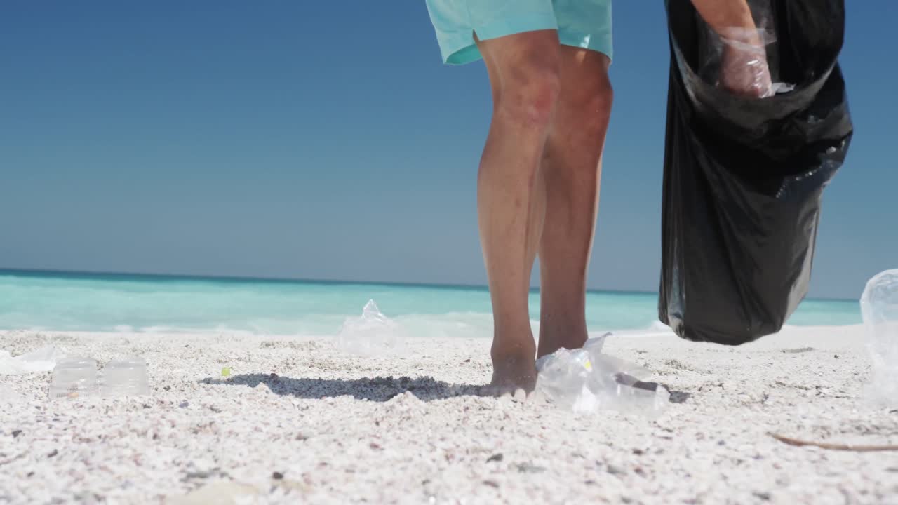 해변 에서 쓰레기 를 모아 쓰레기 가방 에 넣는 사람