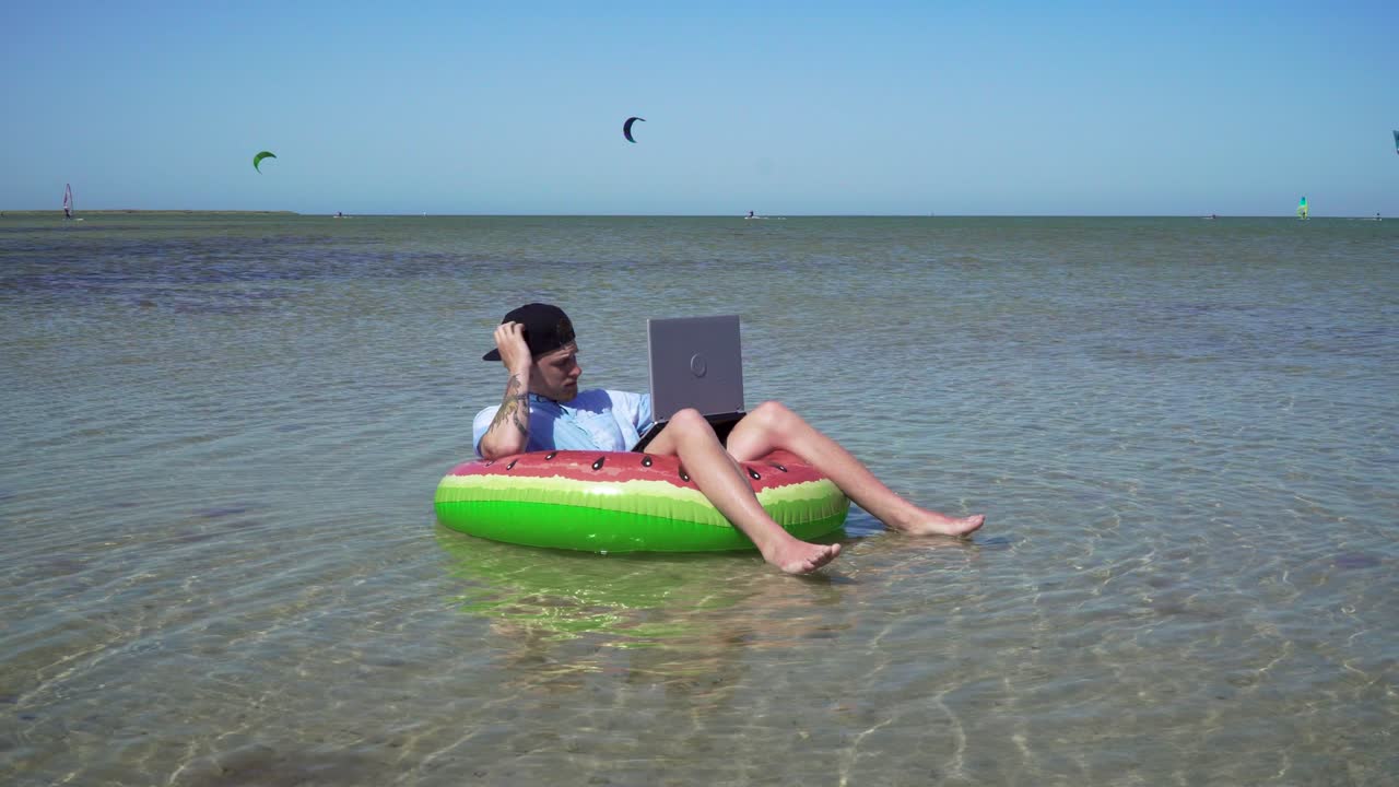 un joven empresario está trabajando con entusiasmo detrás de una computadora portátil balanceándose en las olas del mar