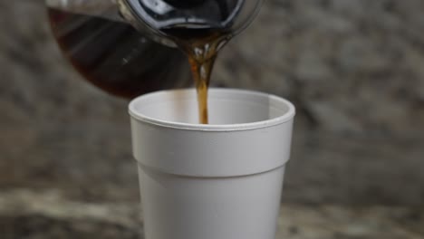 un hombre vierte café en una taza de poliestireno