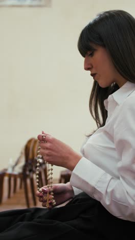 woman praying with a rosary alone in the cathedral