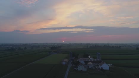 Luftaufnahme-Eines-Sonnenaufgangs-über-Amish-Farm-Landet-An-Einem-Nebligen-Sommermorgen