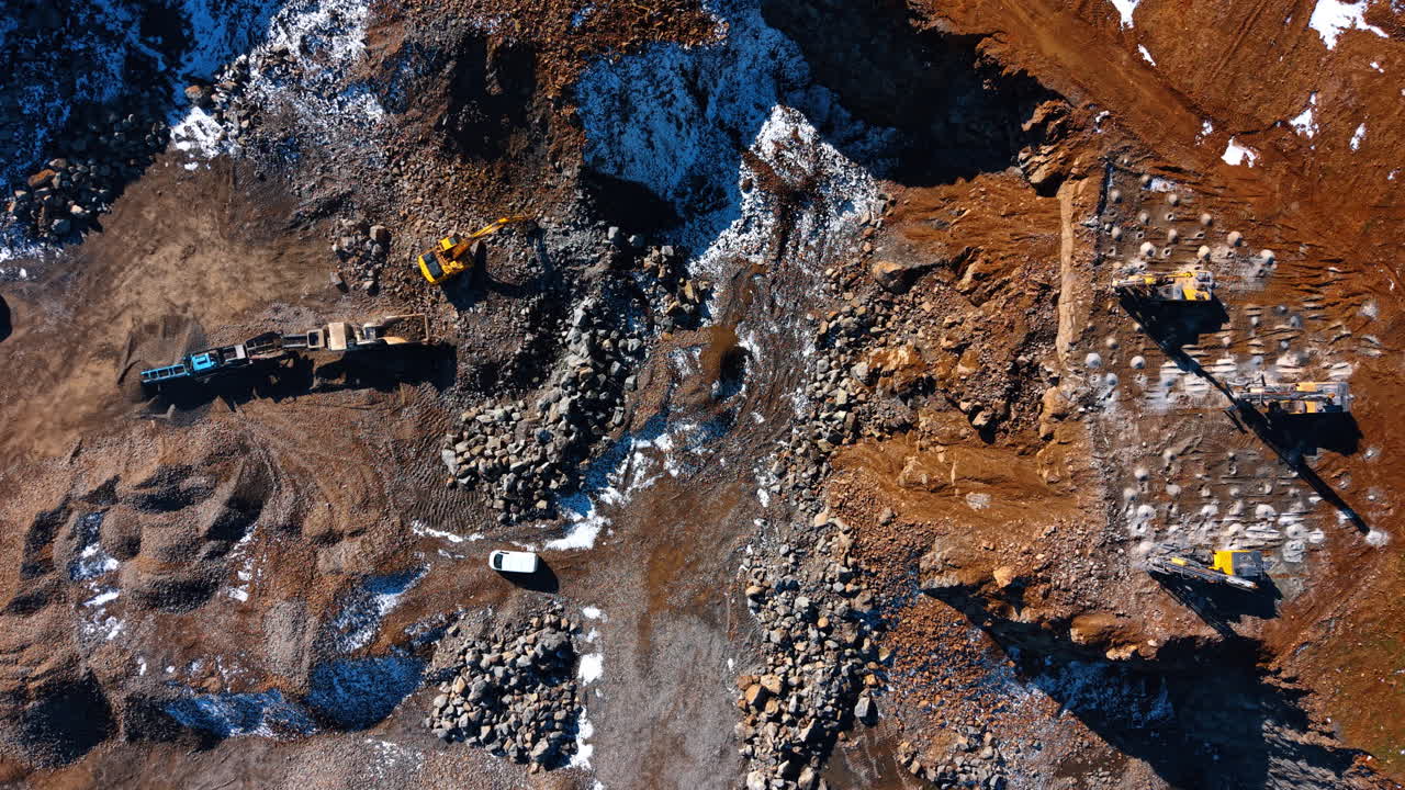 Top down view of mining operations and machinery. Composite view of excavators, mobile crushers, and drill rigs working on different levels of a granite quarry