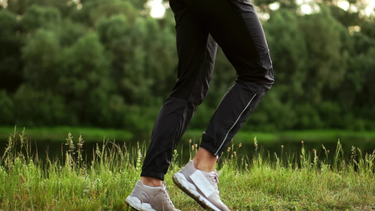 분홍색 재 ⁇ 을 입은 소녀가 러닝을 준비하고 휴대폰을 통해 헤드폰에서 음악을 듣고 있습니다.