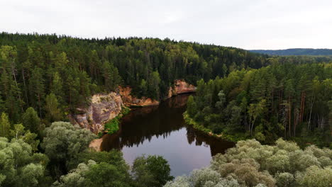 sandstone outcrops of erglu cliffs through gauja river in gauja national park, latvia. aerial drone shot