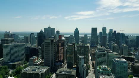 4K-Cinematic-urban-drone-footage-of-an-aerial-view-of-buildings-and-skyscrapers-in-the-middle-of-downtown-Montreal,-Quebec-on-a-sunny-day