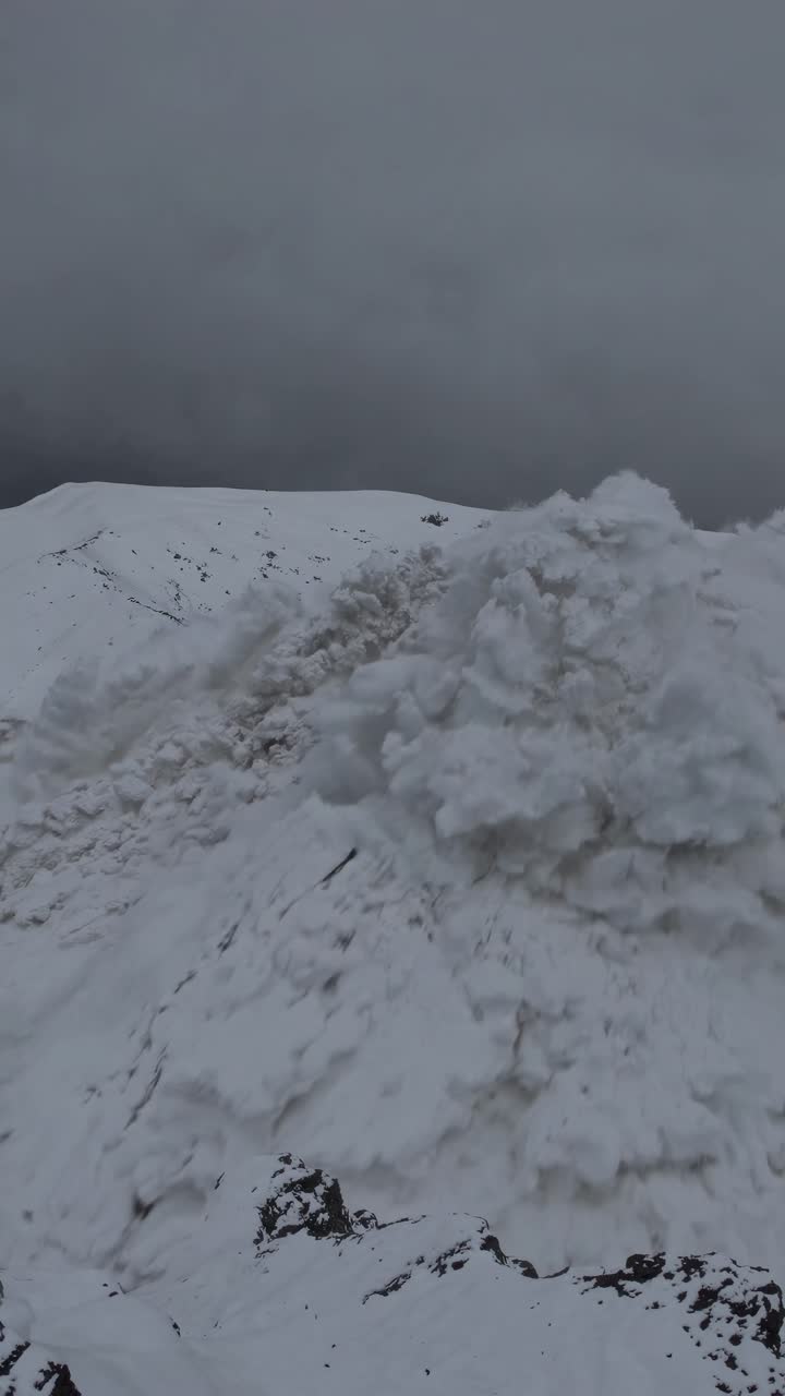 Aerial video captures a dramatic avalanche cascading down a snowy mountain, showcasing nature's
