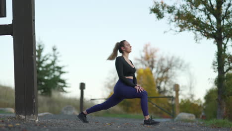 Junge-Frau-Streckt-Ihre-Beine-Vor-Einem-Joggen-Am-Frühen-Morgen-Auf-Einem-Naturlehrpfad