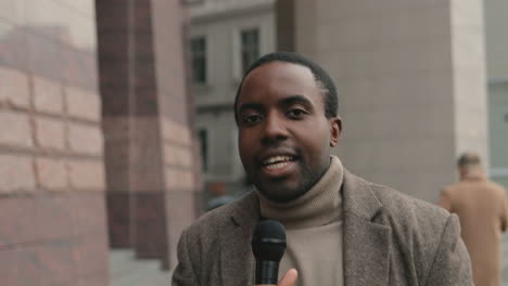 Close-up-view-of-African-American-man-journalist-speaking-on-the-microphone-while-recording-a-story-for-evening-news