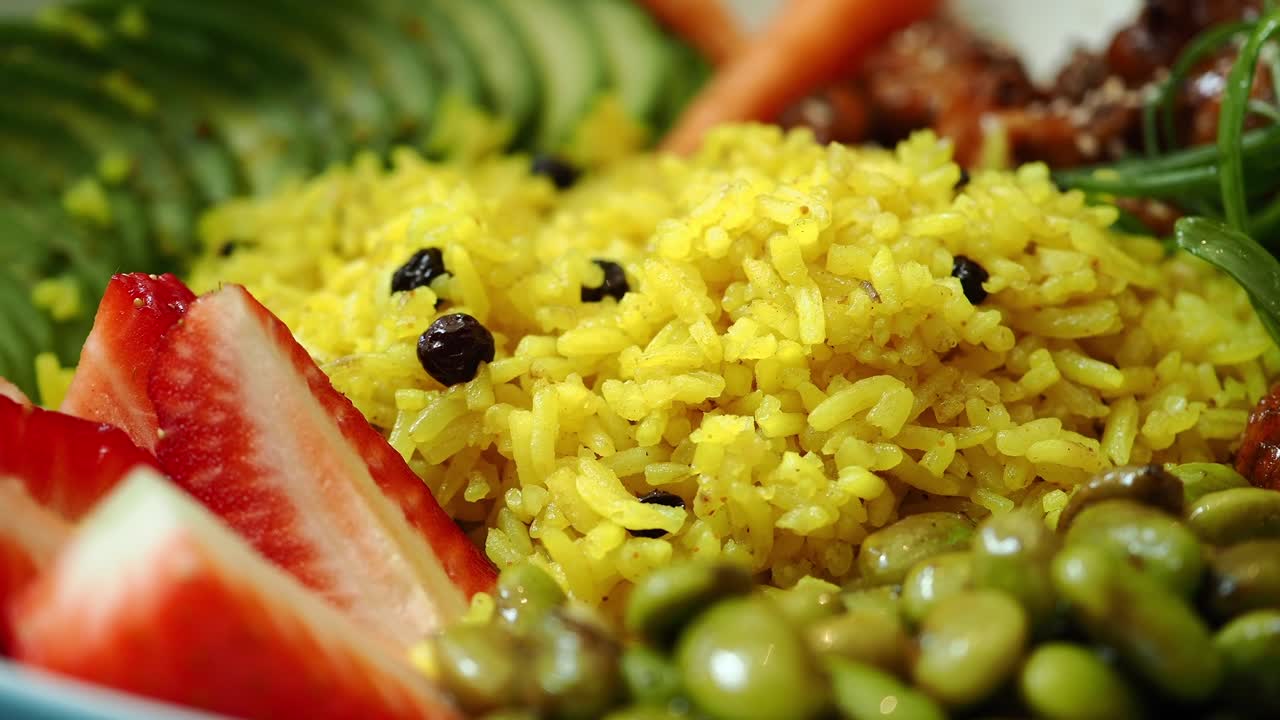 Ciotola pasto vibrante e salutare con riso giallo e ingredienti freschi.