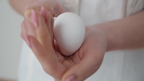 female hands squeezing bottle of body cream, forming soft white ball on palm