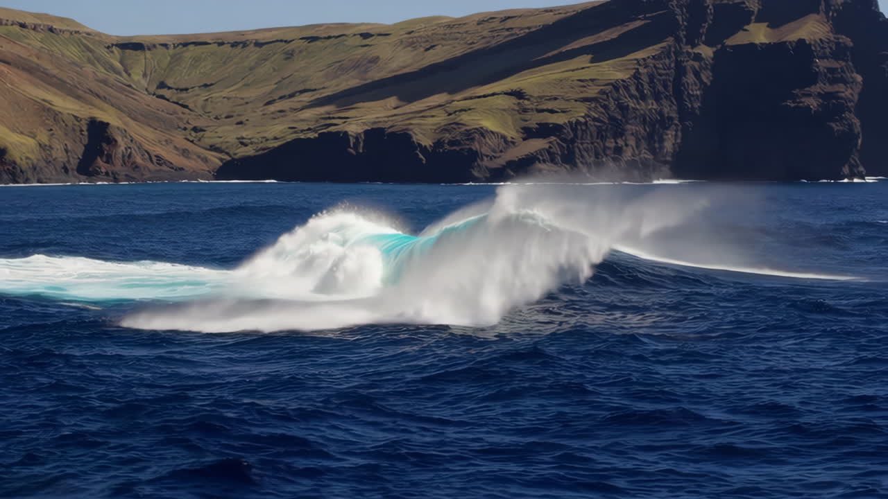 A powerful ocean wave breaking with a large island cliff in the background