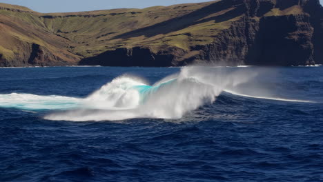 a powerful ocean wave breaking with a large island cliff in the background