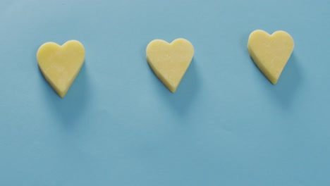 video of row of heart shapes of cheese on blue background with copy space