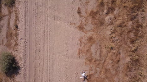 white consumer drone sits along sandy desert road path before launch