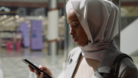 black lady with hijab holds phone in shopping mall elevator