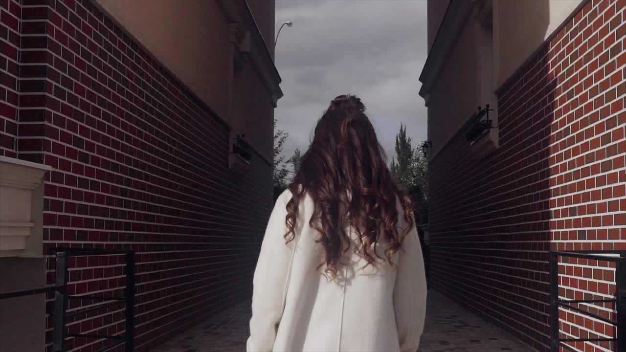 Woman in a white coat in an urban alley