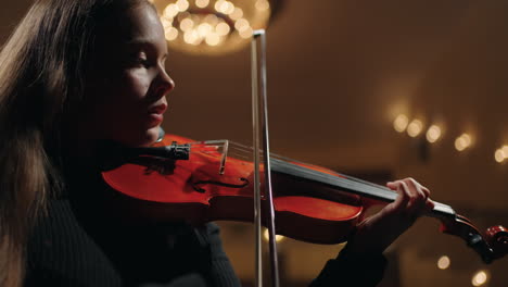 symphonic orchestra in opera house female violinist is playing classic music in dark philharmonic hall