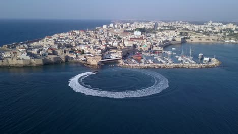 acre israel: aerial footage of the old city and port of acre or akko, israel. speed boat at sea.