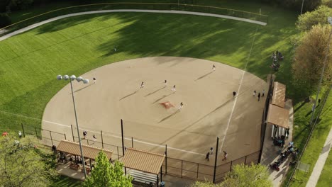 aerial drone shot. kids play school baseball field at park on sunny day