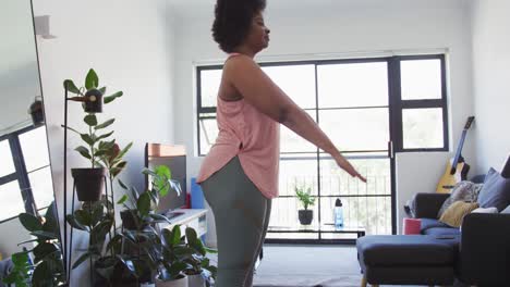 african american female plus size standing on exercise mat doing sit ups