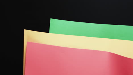 video of red, yellow and green papers with copy space on black background