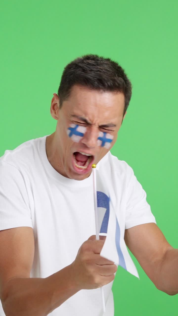 Man cheering for Finland waving a national flag looking away