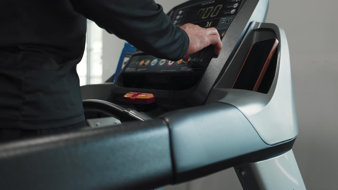 A man stands on a treadmill inside a modern gym. Fitness gym footage
