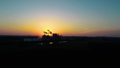 Drone-shot-of-ethanol-plant-silhouetted-as-sun-rises-over-the-horizon