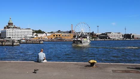 harbor vew with man sitting next to water at port of helsinki, finland