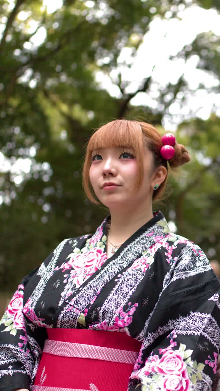 Una giovane donna che indossa un kimono floreale tradizionale sta in piedi con calma in una foresta verde lussureggiante