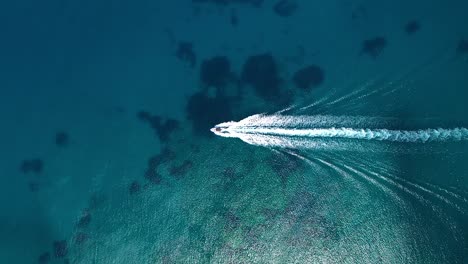 motorboat leaves wave trail in blue ocean, aerial view from above