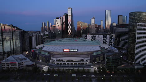 drone rising in front of the marvel stadium entrance, blue hour in melbourne